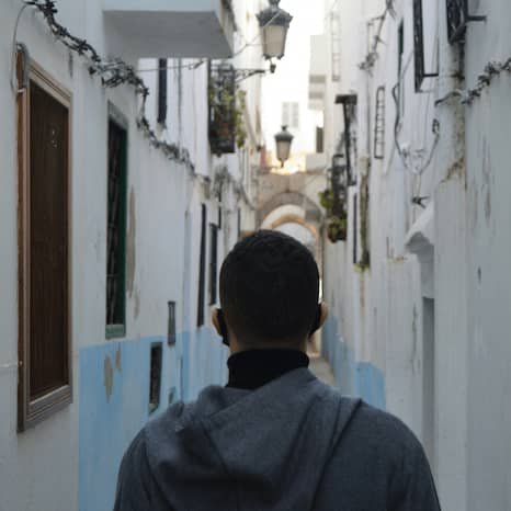 A man walking down a narrow street in Tetouan